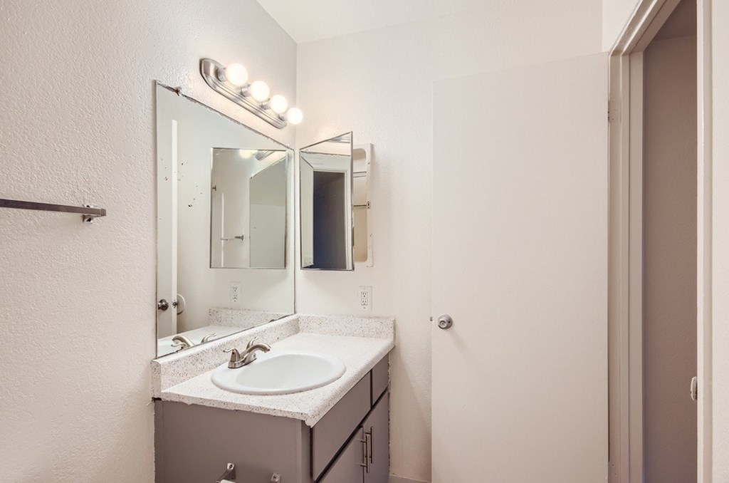 A bathroom with a sink, mirror, and lights.