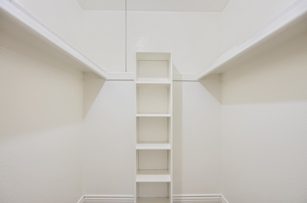 A white shelf in the middle of a white room.