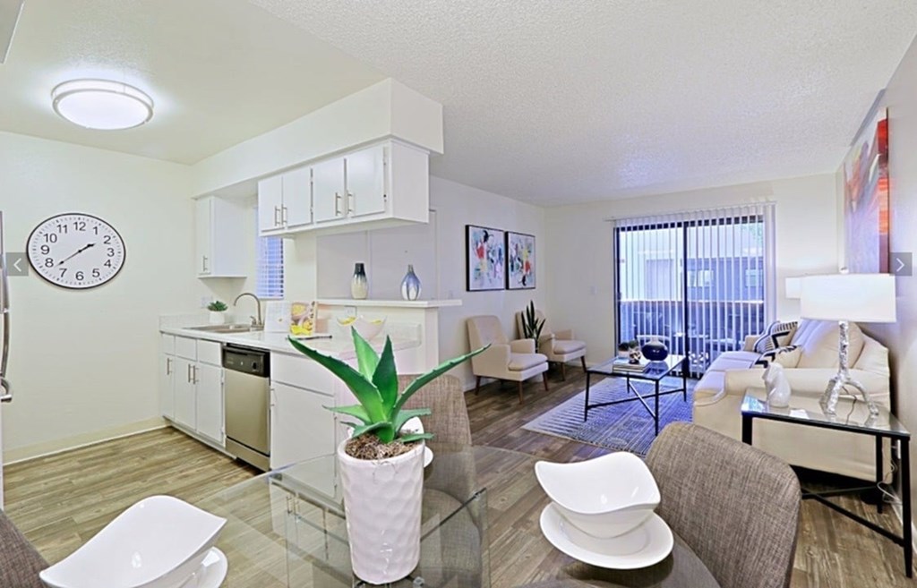 A modern kitchen with white cabinets and a glass table with a plant on it.