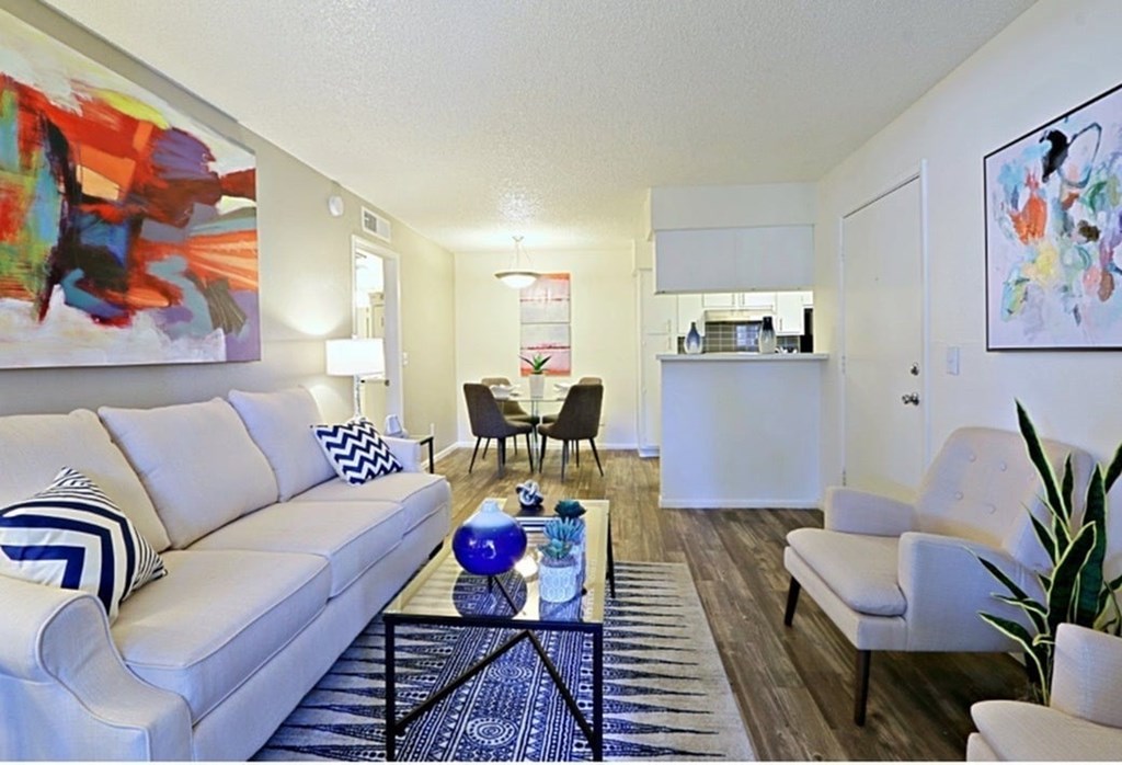 A living room with a white couch and a painting on the wall.