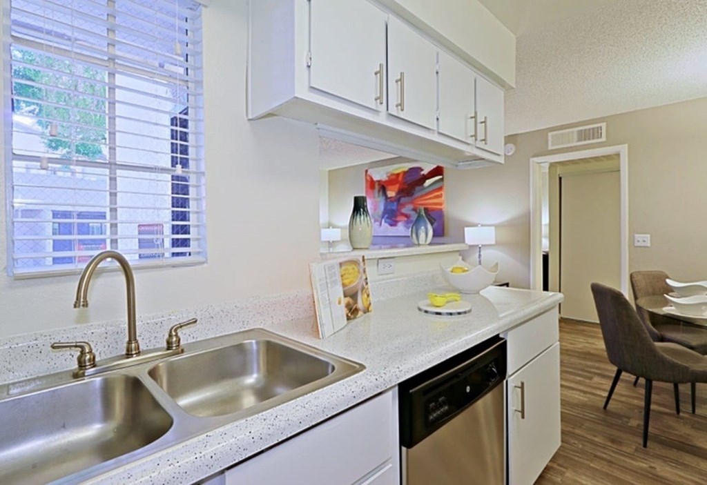 A kitchen with a sink, stove, and a chair.
