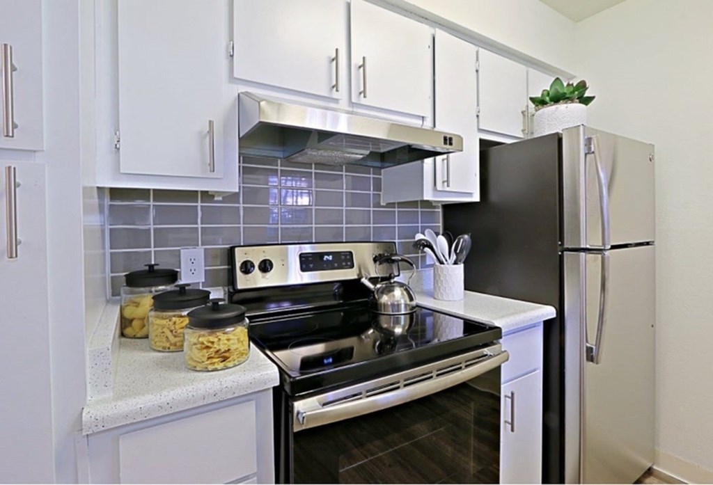 A kitchen with a black stove top and white cabinets.