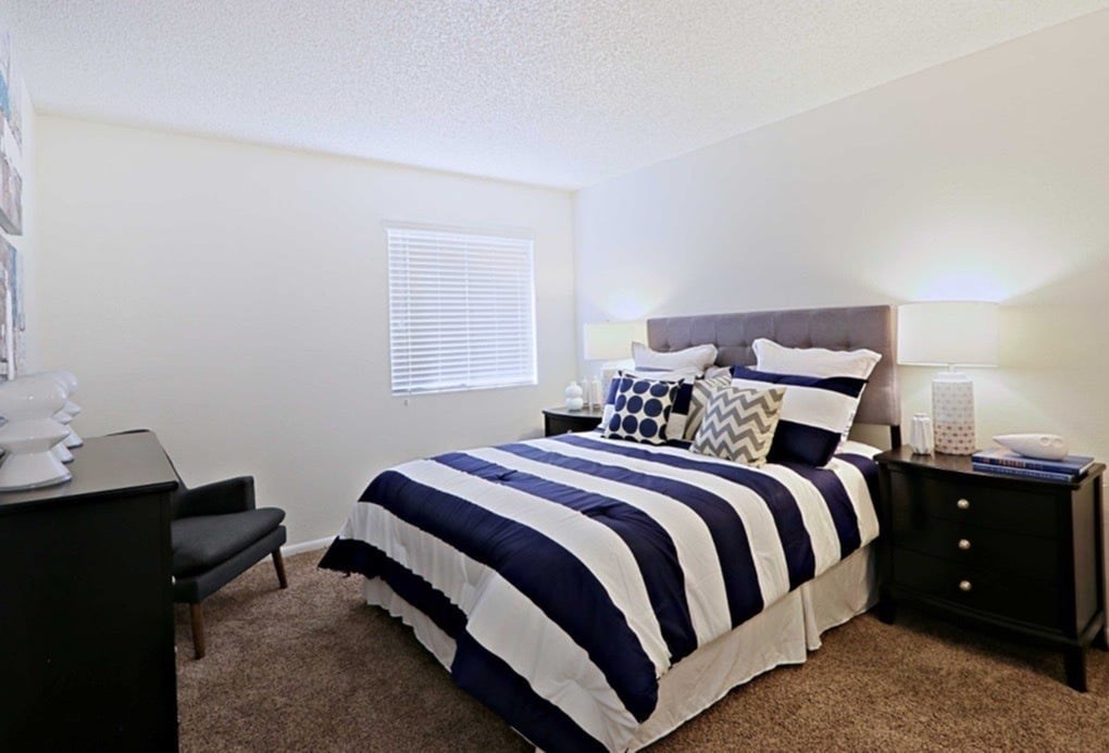 A bedroom with a bed, nightstand, and chair.