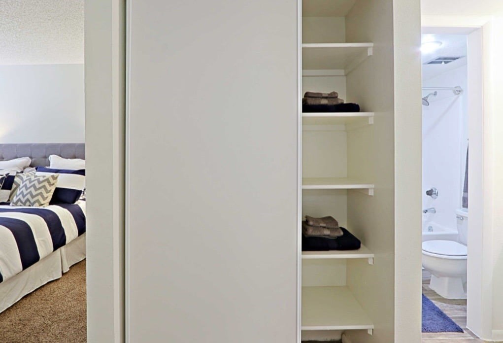 A white closet with shelves and clothes on it.
