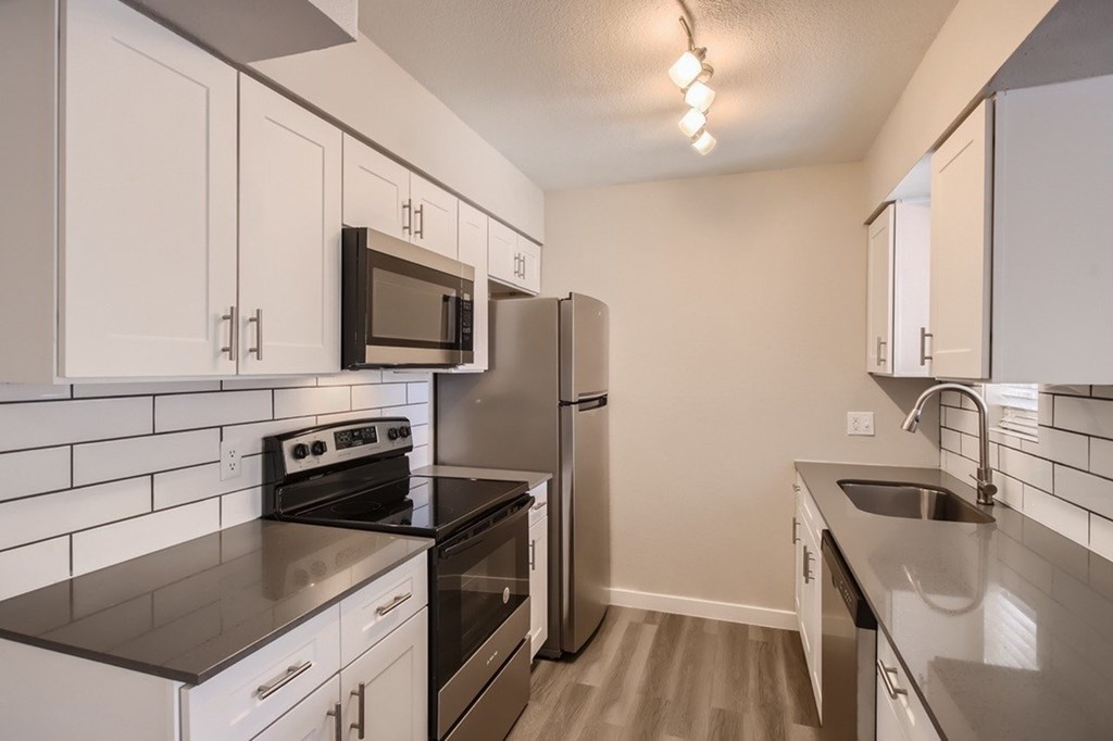 A kitchen with white cabinets and black countertops.