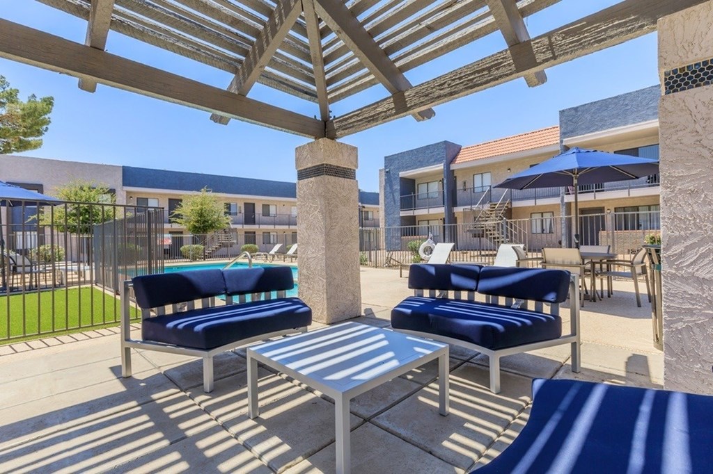 A patio with a table and chairs under a wooden pergola.
