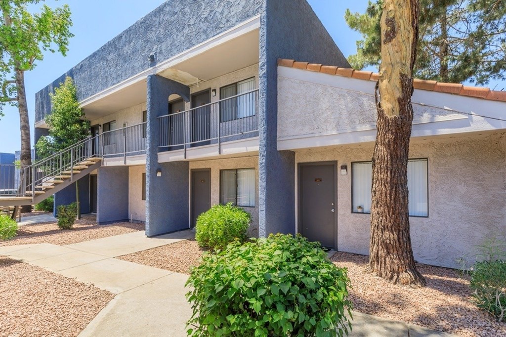 A building with a grey roof and a tree in front.