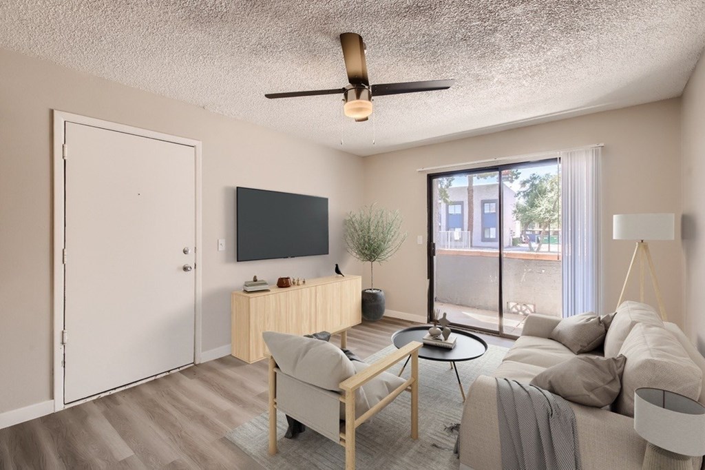 A living room with a couch, a chair, a coffee table, a television, and a plant.