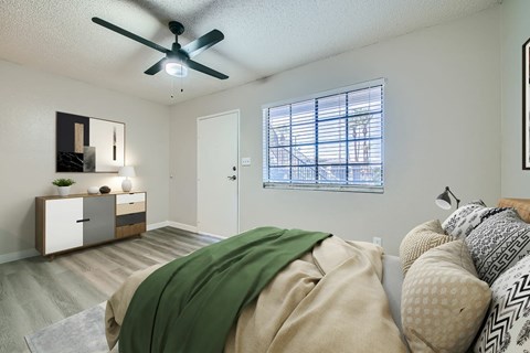 A bedroom with a bed covered in a green blanket.