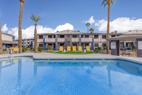 A swimming pool in front of a building with palm trees.