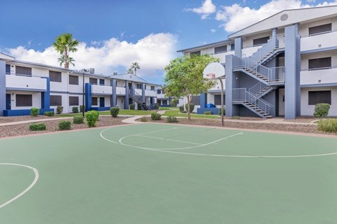 A basketball court is surrounded by apartment buildings.