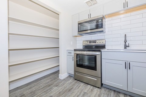 A modern kitchen with a stainless steel oven and microwave above it.