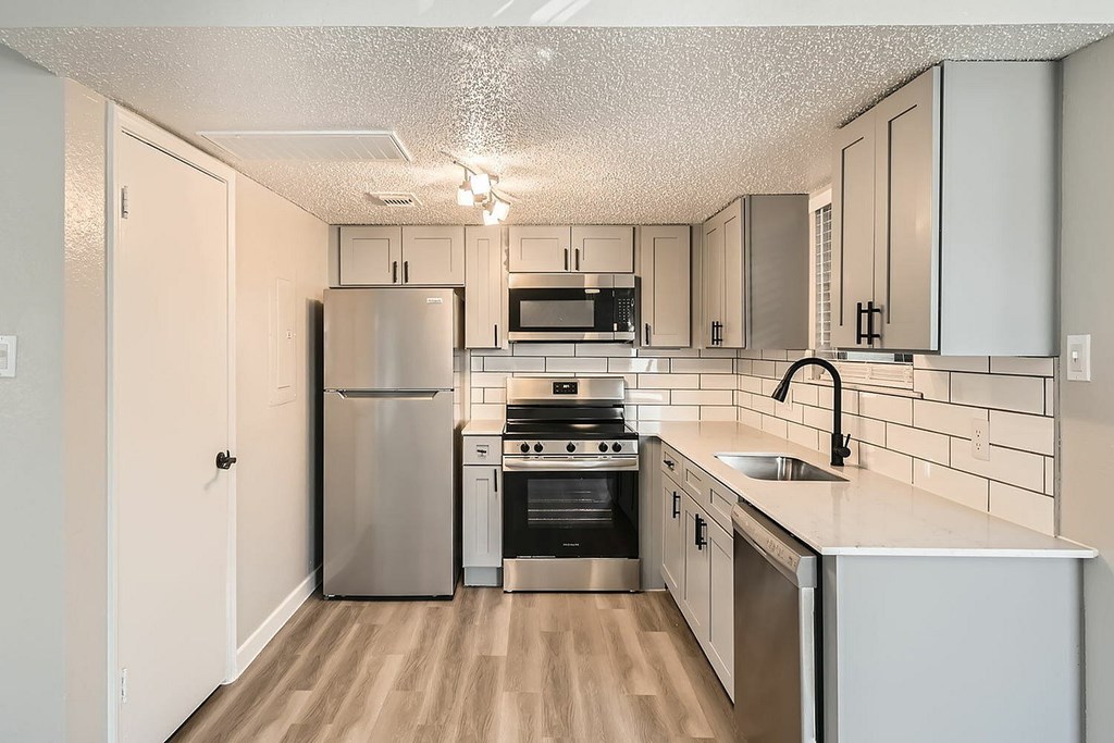 A kitchen with a stainless steel refrigerator, oven, and microwave.