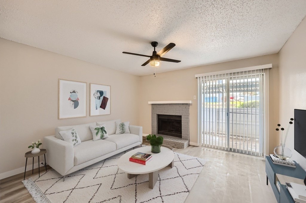 A living room with a white couch, a fireplace, and a ceiling fan.