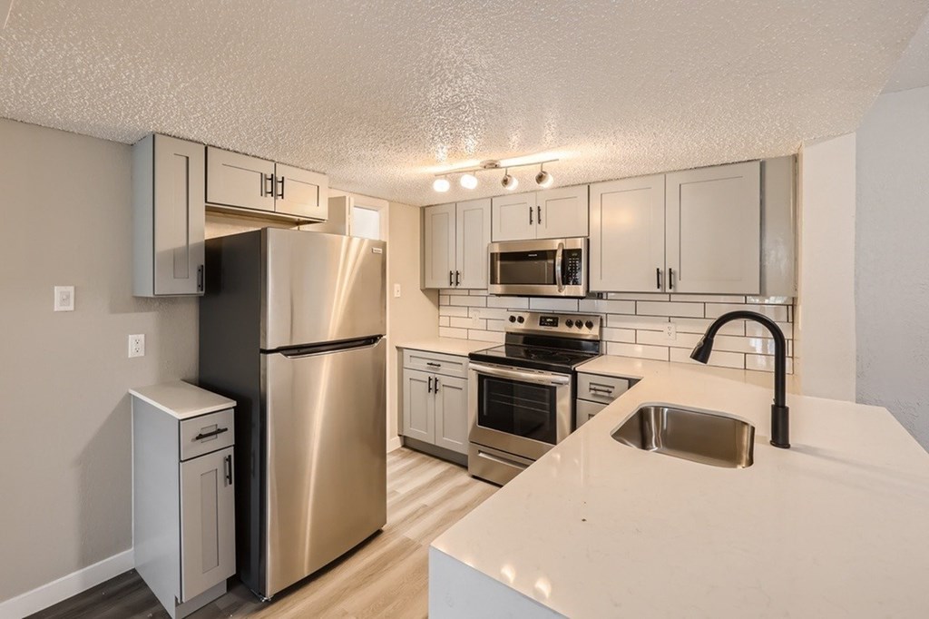 A kitchen with a stainless steel refrigerator and a white countertop.