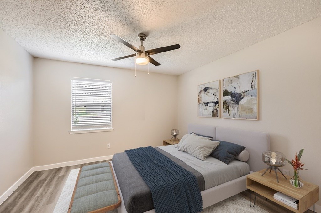 A bedroom with a bed, a ceiling fan, and a window with blinds.