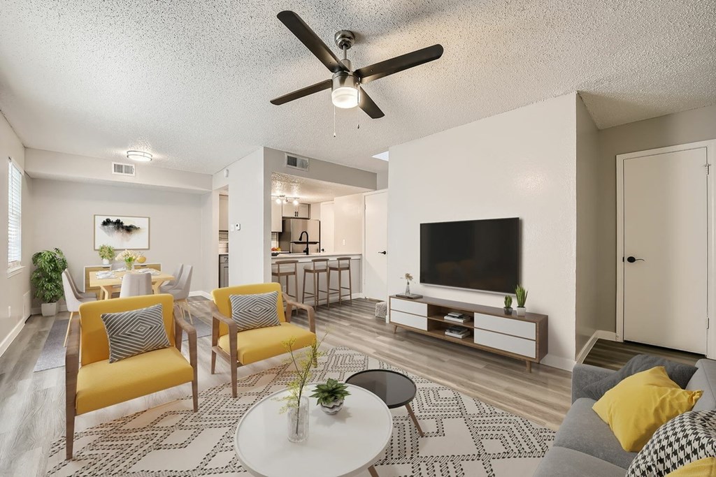 A living room with a yellow chair and a white ceiling fan.