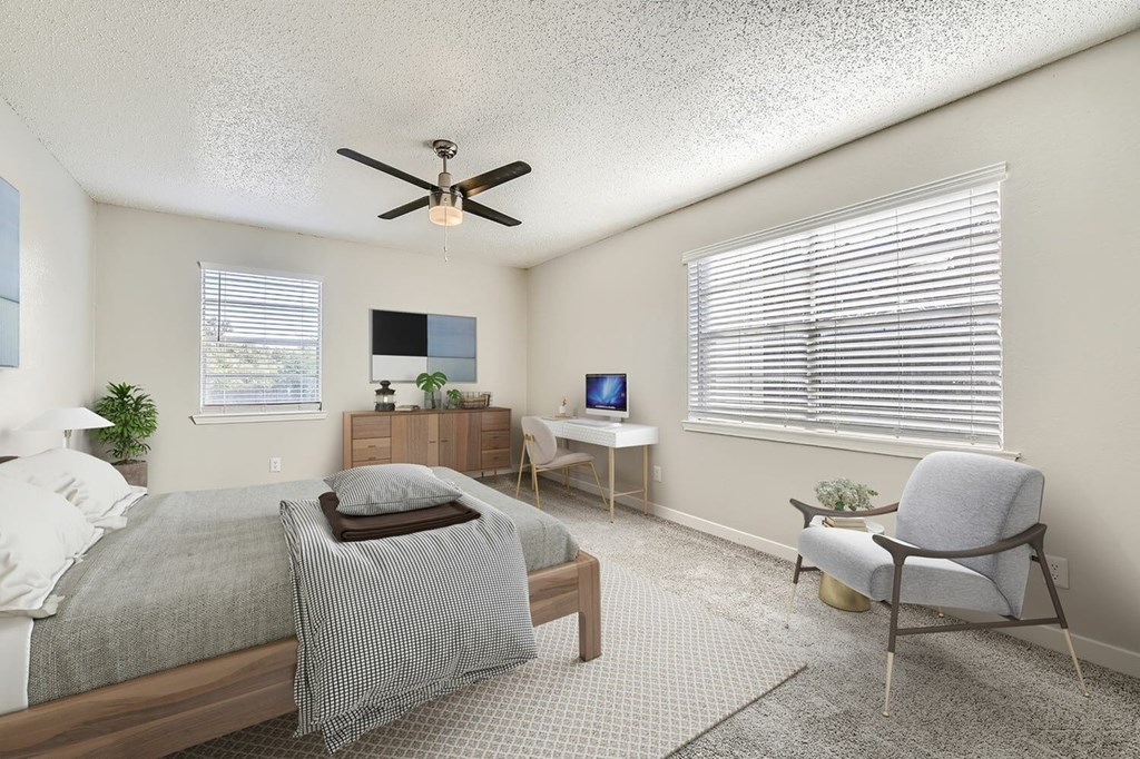 A bedroom with a bed, chair, and ceiling fan.