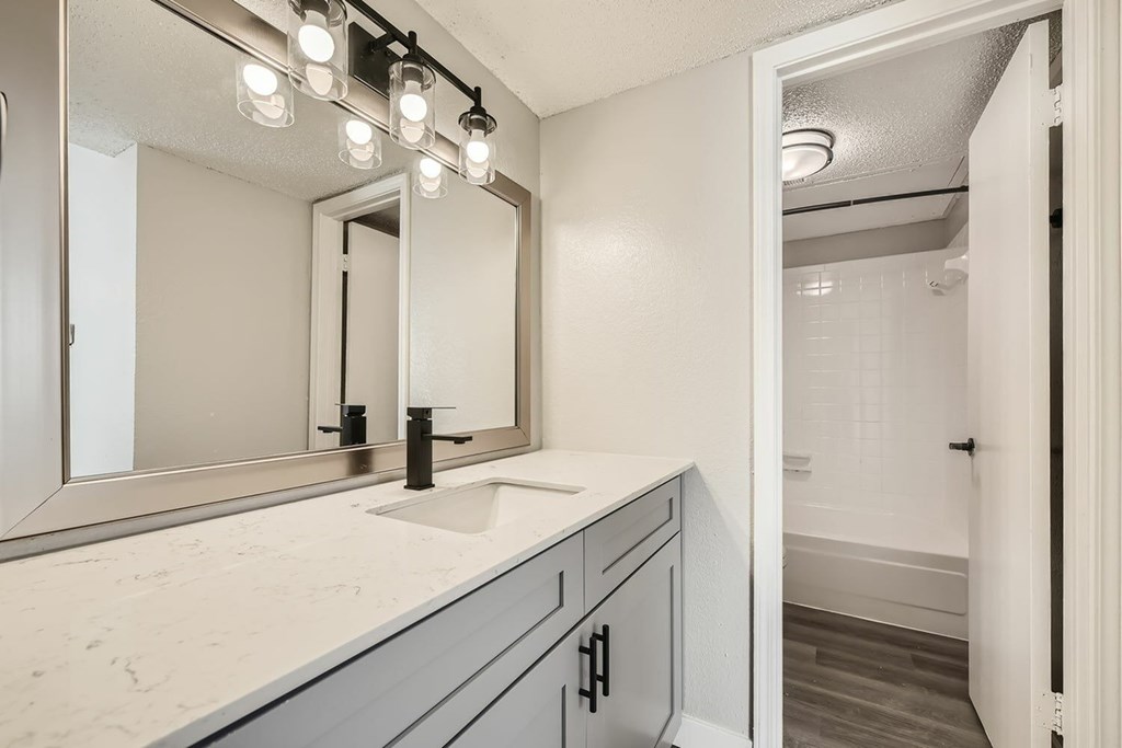A bathroom with a sink, mirror, and lights.