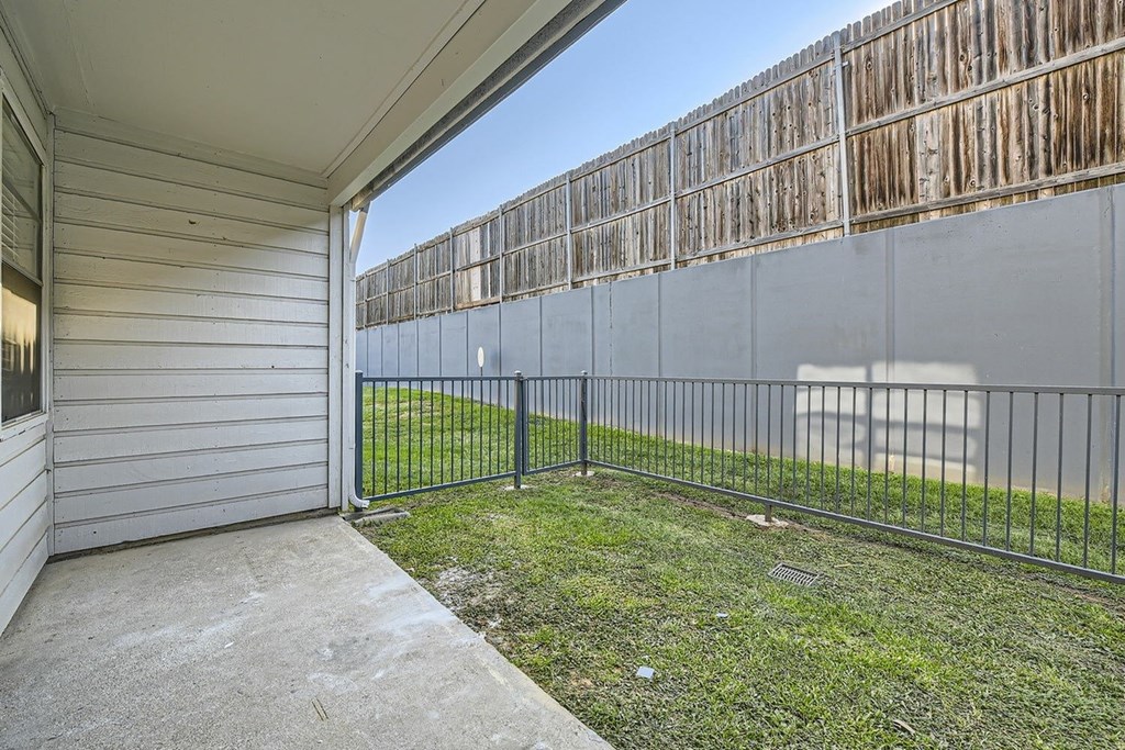 A patio area with a black fence and a wooden wall in the background.