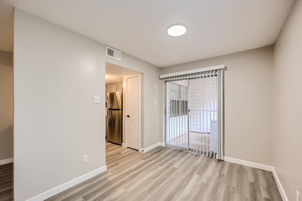 A kitchen area with a refrigerator and a dining table with chairs.