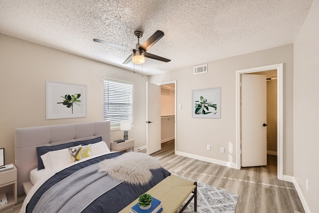A bedroom with a bed, a ceiling fan, and two framed pictures on the wall.