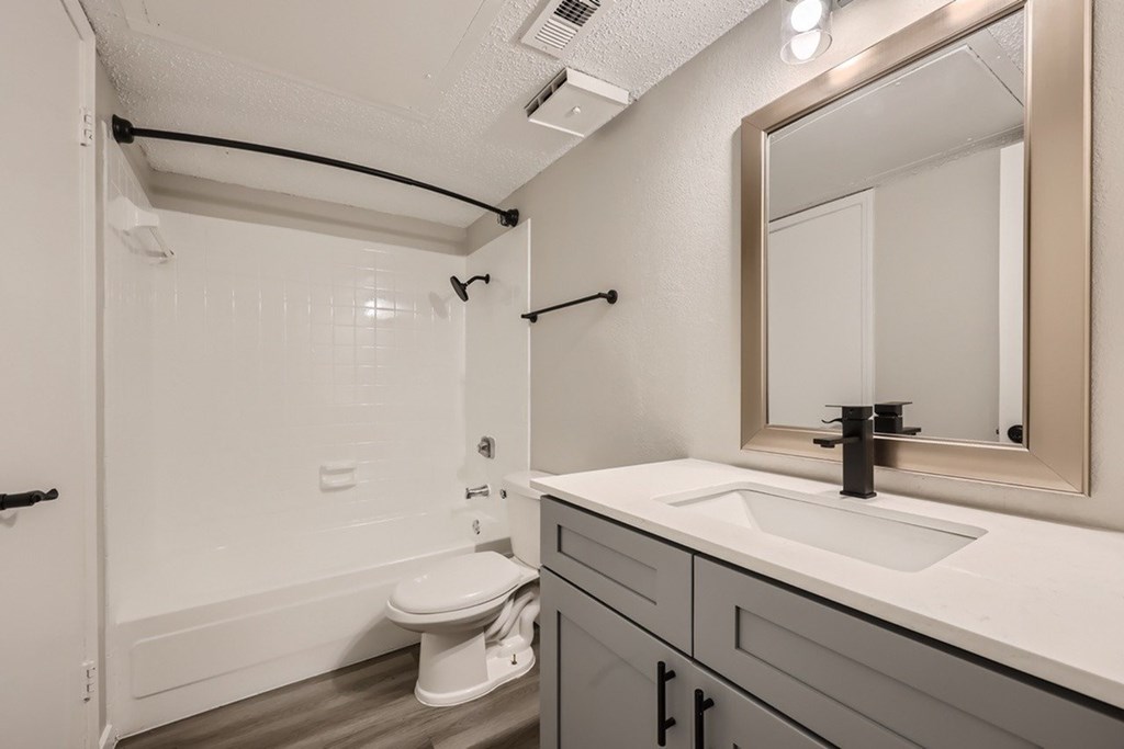A white bathroom with a toilet, sink, and mirror.