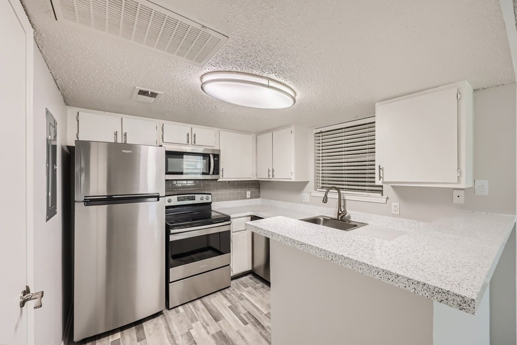 A kitchen with a stainless steel refrigerator and white cabinets.