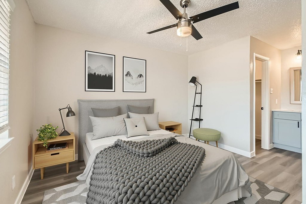 A bedroom with a bed, a ceiling fan, and two pictures on the wall.
