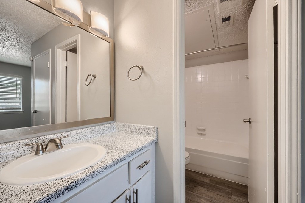 A bathroom with a sink, mirror, and towel rack.