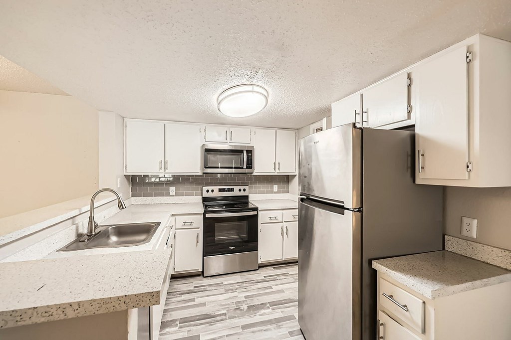 A kitchen with a refrigerator, sink, and oven.