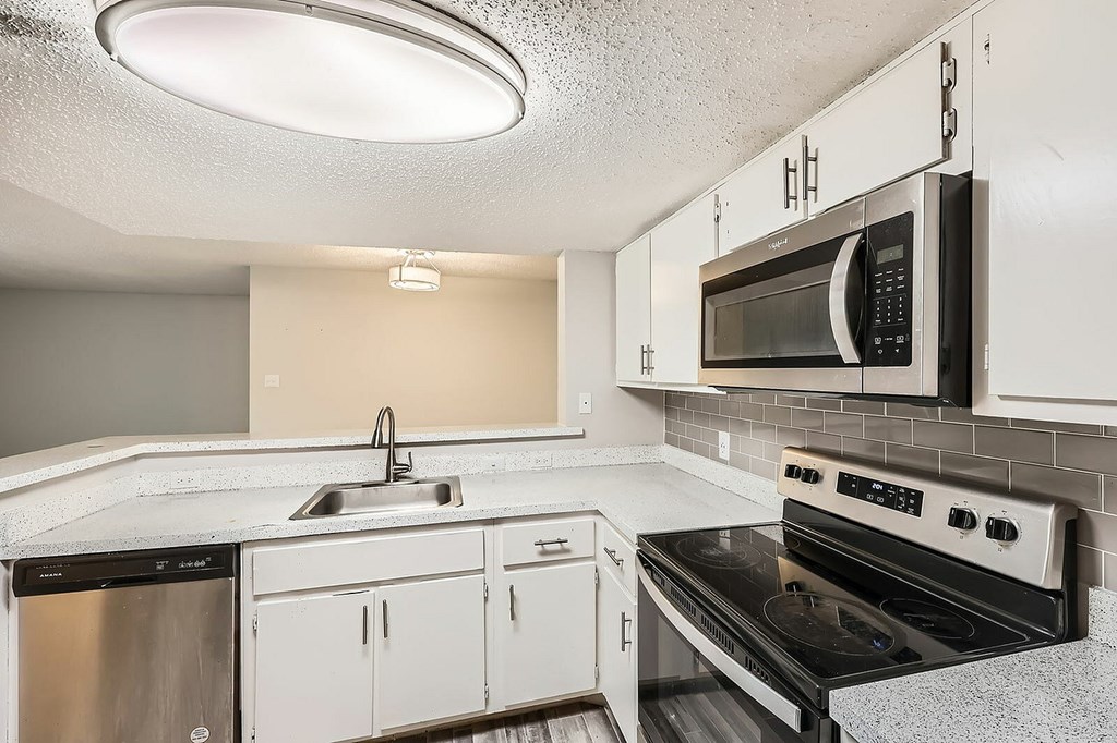 A kitchen with a black microwave above a stove.