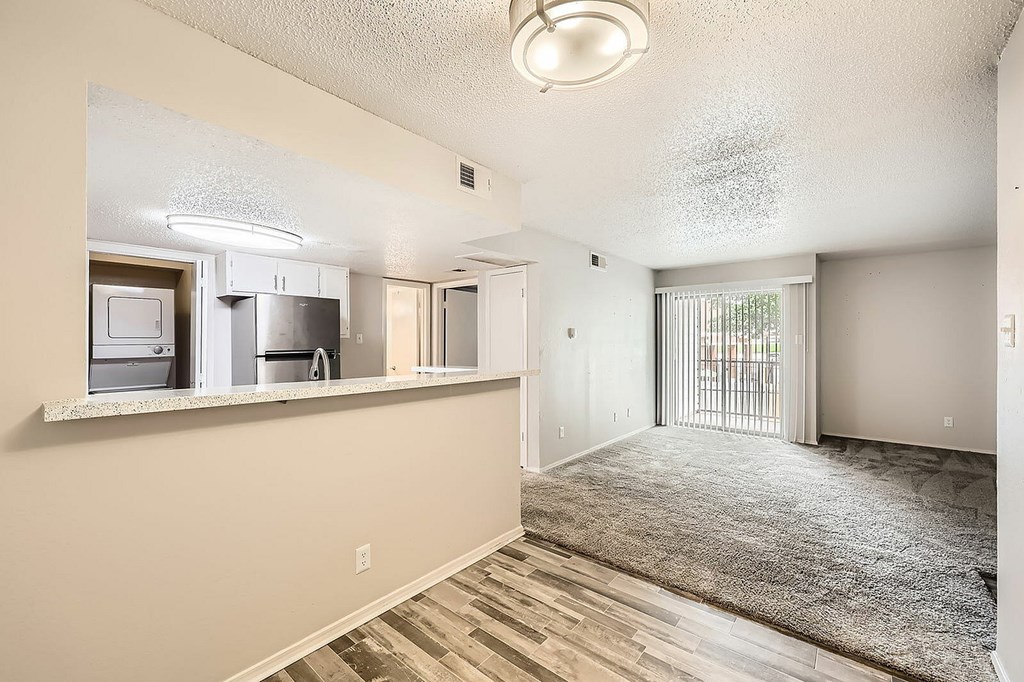 A spacious living room with a kitchen area in the background.