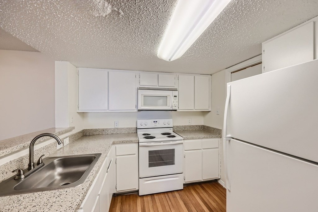 A kitchen with white cabinets and appliances.