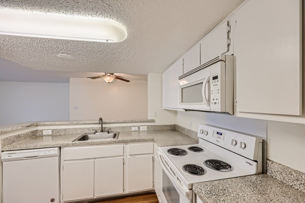 A kitchen with a white stove top oven and a microwave above it.