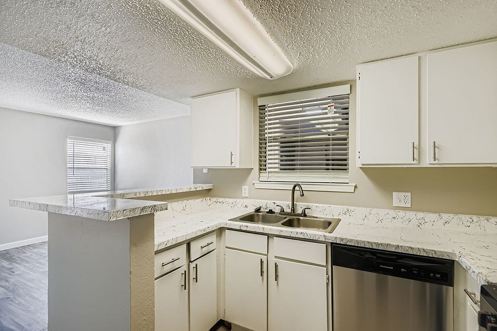 A large, empty room with a carpeted floor and a window with curtains.