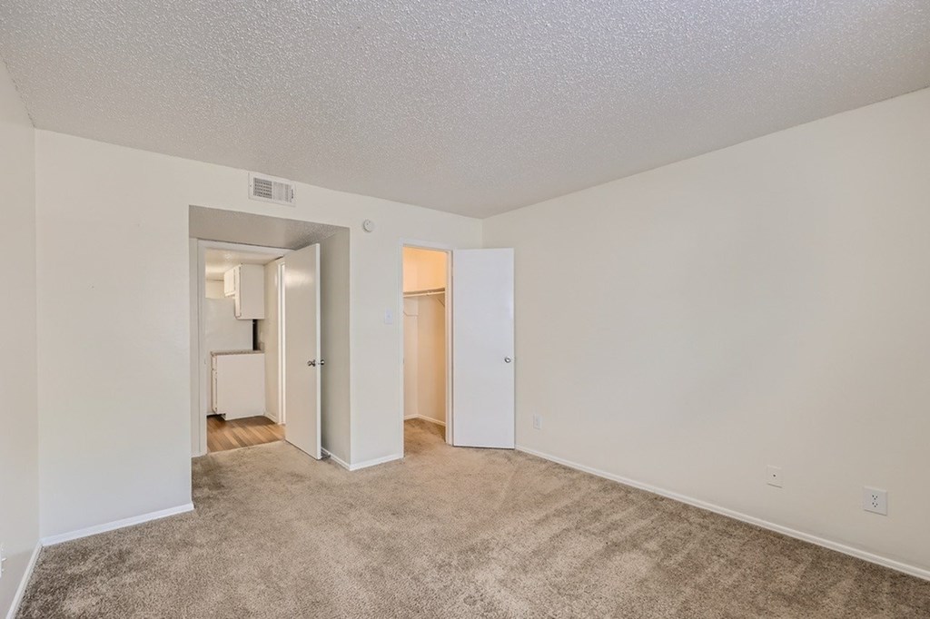 A room with carpeted floor and two doors.