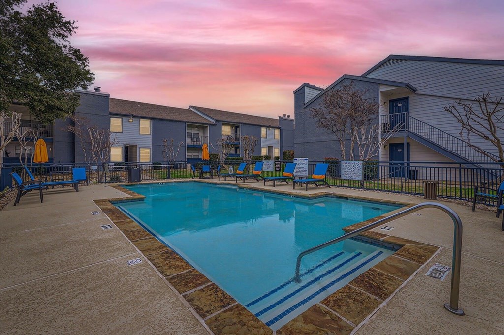 A swimming pool surrounded by a fence and a building in the background.