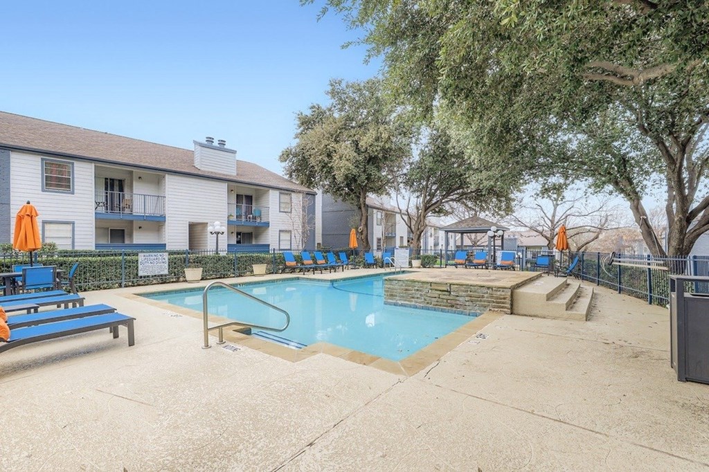 A swimming pool surrounded by a concrete patio and a fence.