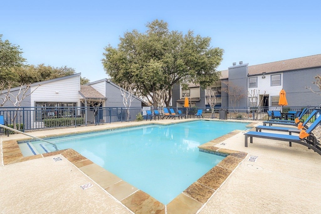 A large outdoor swimming pool with a diving board and lounge chairs.