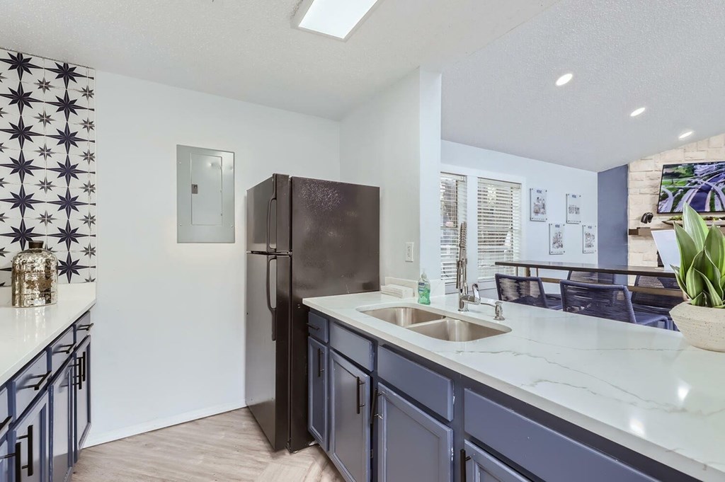 A kitchen with a black refrigerator and a white countertop.