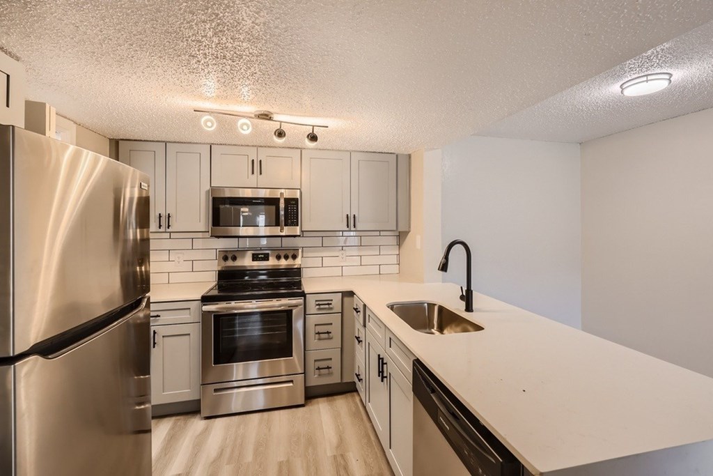 A kitchen with a stainless steel refrigerator, oven, and microwave.