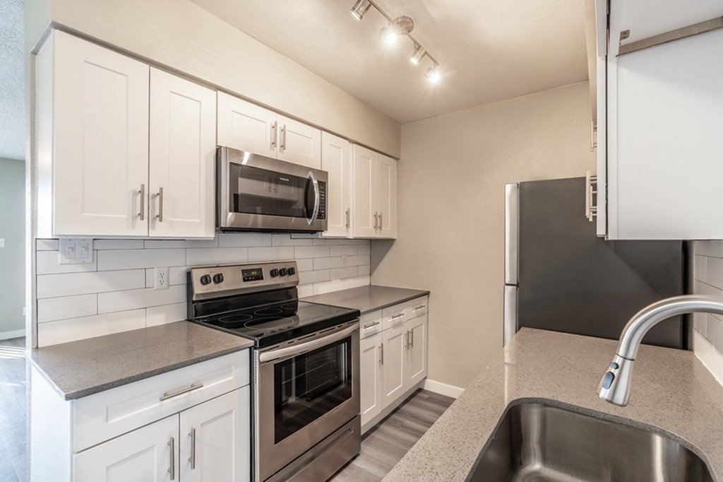 A kitchen with white cabinets and a stainless steel oven.