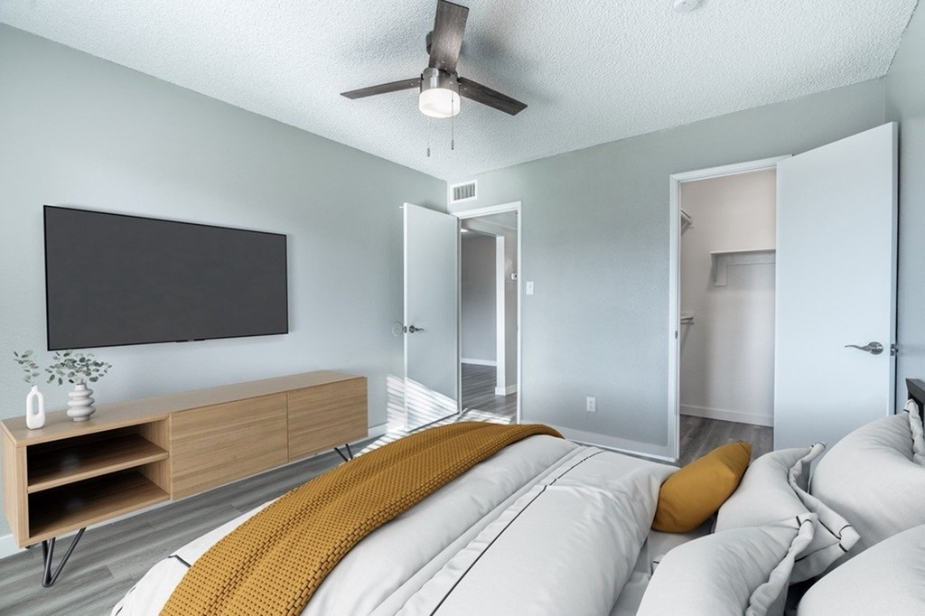 A modern bedroom with a large bed and a flat screen TV on the wall.
