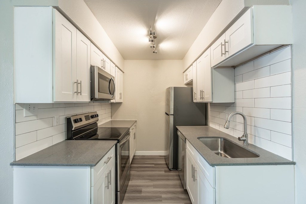A kitchen with white cabinets and a black refrigerator.