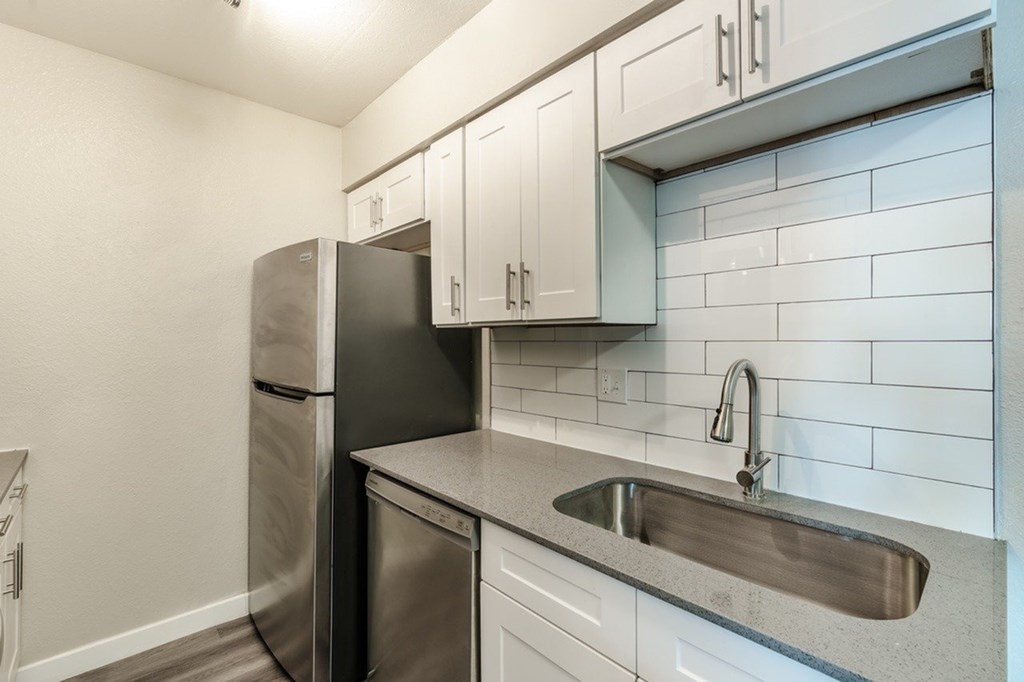 A kitchen with a black fridge and stainless steel dishwasher.