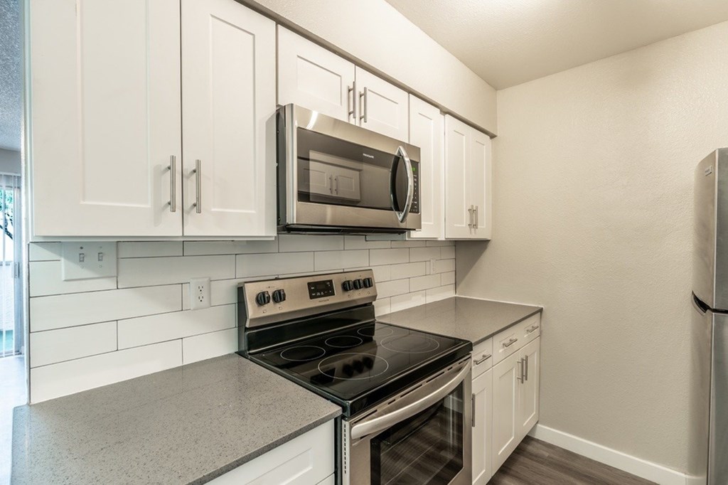 A kitchen with a black stove top oven and a microwave above it.