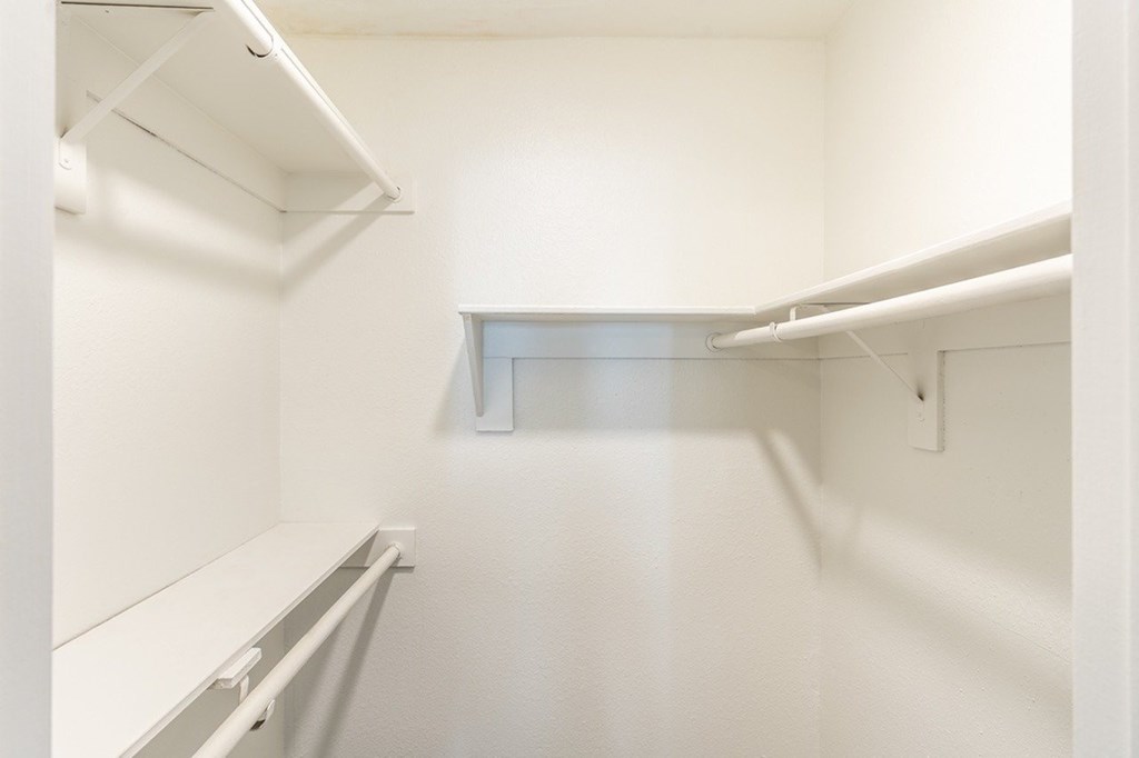 A white walk in closet with shelves and a door.
