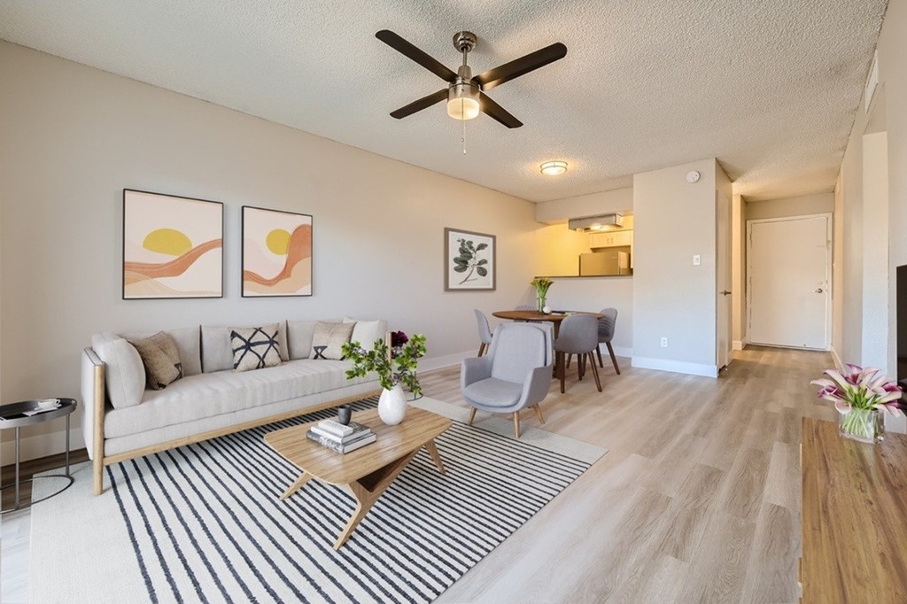 A living room with a white couch, a coffee table, and a ceiling fan.