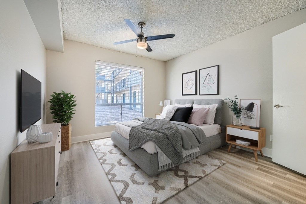 A bedroom with a bed, a television, and a plant.